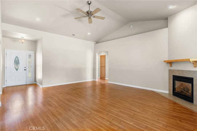 unfurnished living room with a fireplace, lofted ceiling, light hardwood / wood-style flooring, and ceiling fan