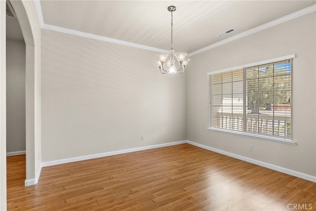 spare room with an inviting chandelier, hardwood / wood-style flooring, and crown molding