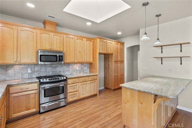 kitchen featuring light stone counters, decorative light fixtures, backsplash, appliances with stainless steel finishes, and light hardwood / wood-style floors