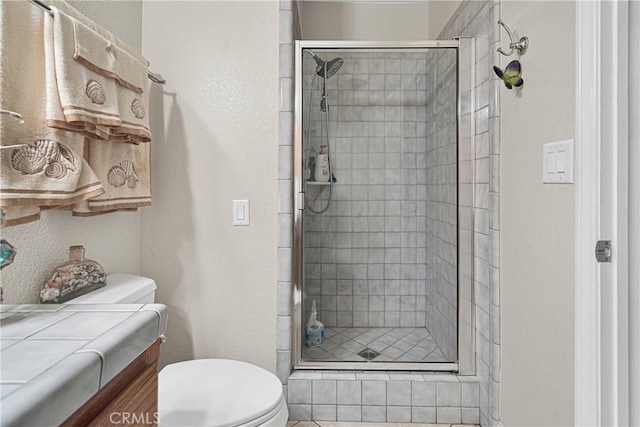 bathroom featuring a shower with door, toilet, and vanity