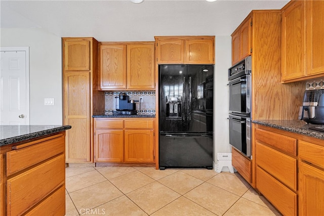 kitchen featuring dark stone countertops, black appliances, light tile patterned floors, and tasteful backsplash