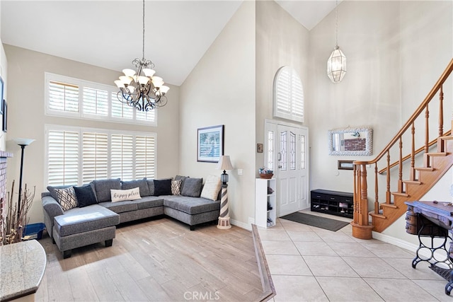 living room featuring high vaulted ceiling, light hardwood / wood-style floors, and an inviting chandelier