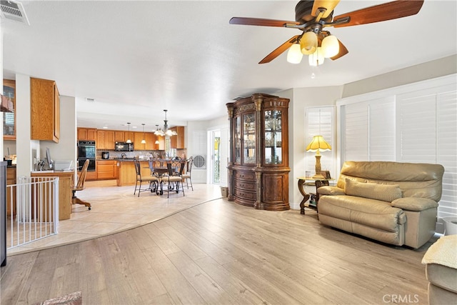 living room featuring ceiling fan and light hardwood / wood-style floors