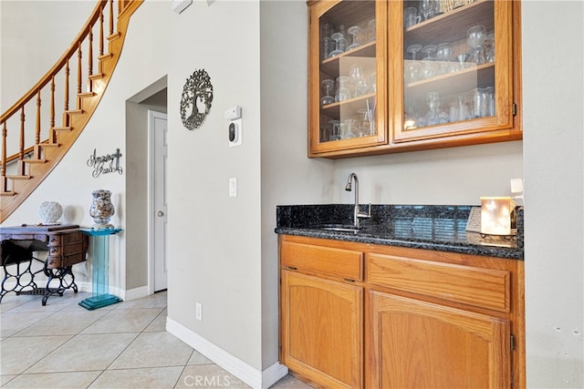 bar featuring light tile patterned floors, sink, and dark stone counters