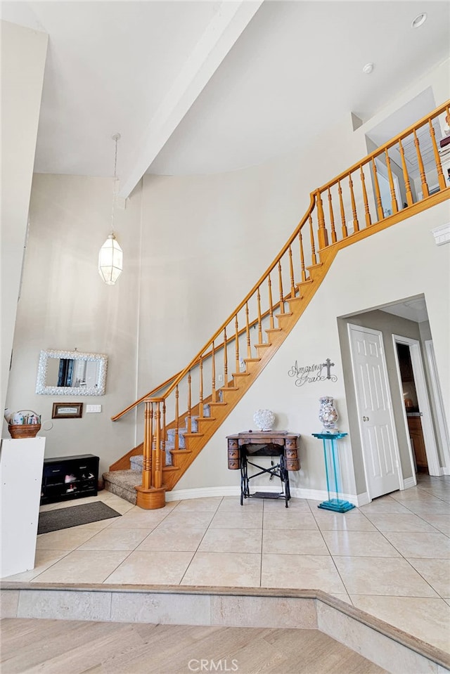 stairs with tile patterned flooring and a high ceiling