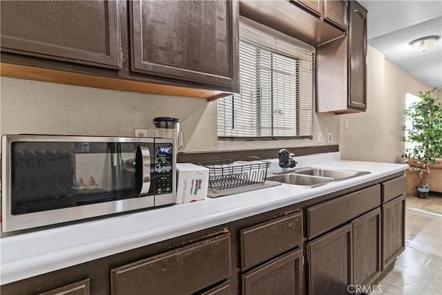 kitchen with dark brown cabinets, light tile patterned floors, and sink