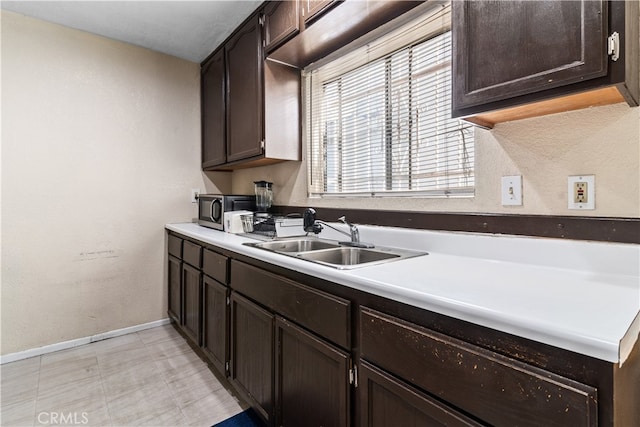 kitchen with light tile patterned floors, sink, and dark brown cabinetry