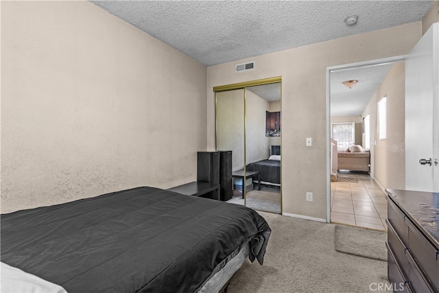 carpeted bedroom featuring a textured ceiling and a closet