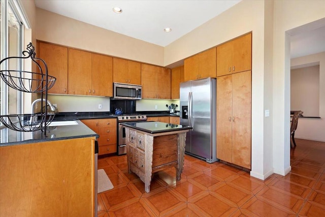 kitchen with sink, appliances with stainless steel finishes, light tile patterned flooring, and a kitchen island