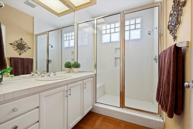 bathroom with tile patterned flooring, a shower with door, a healthy amount of sunlight, and vanity