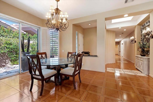 dining space with light tile patterned floors, a skylight, and a chandelier