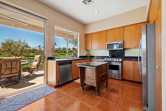 kitchen with light tile patterned floors, appliances with stainless steel finishes, a center island, and sink