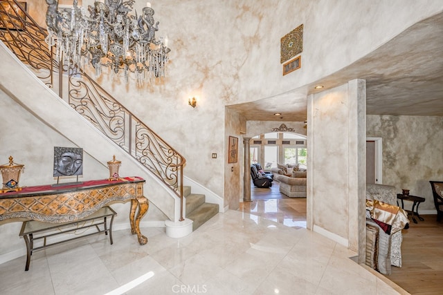 tiled foyer entrance with a chandelier and a towering ceiling