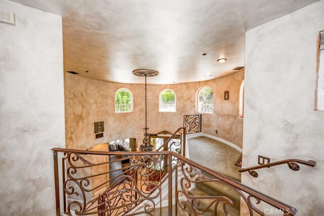 stairway featuring a notable chandelier and concrete flooring