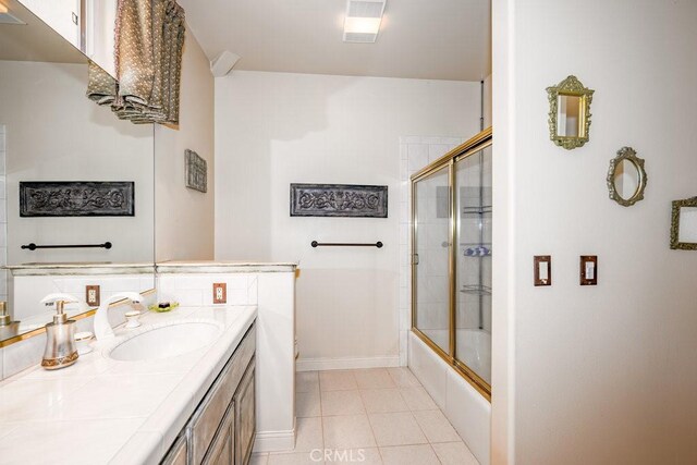 bathroom featuring tile patterned flooring, vanity, and enclosed tub / shower combo