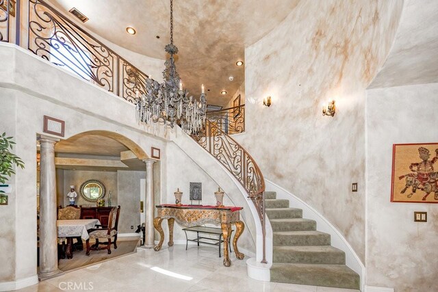 staircase featuring tile patterned floors, ornate columns, and a towering ceiling