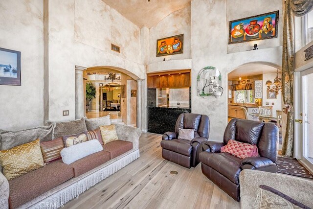 living room with sink, high vaulted ceiling, decorative columns, and light hardwood / wood-style flooring