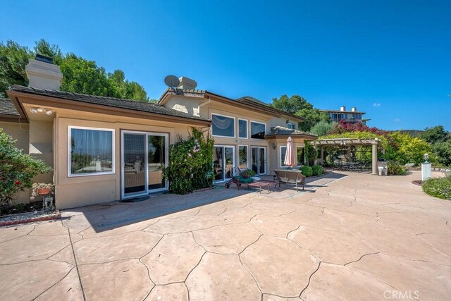 back of property with a pergola and a patio area