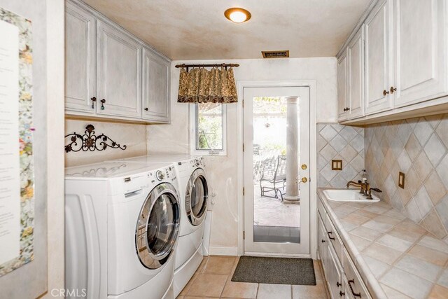 laundry room with light tile patterned floors, washing machine and clothes dryer, cabinets, and sink