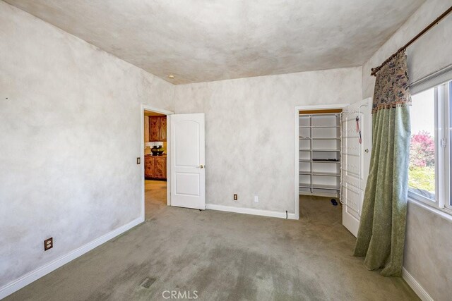 unfurnished bedroom with a closet, a spacious closet, and carpet floors