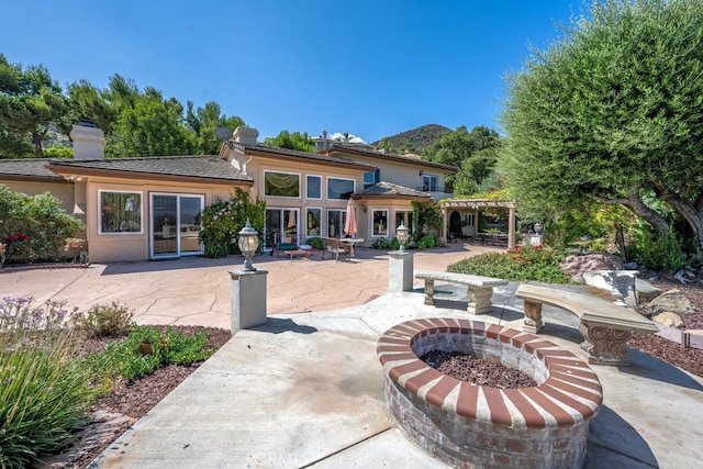 rear view of house with an outdoor fire pit and a patio