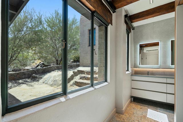 interior space with beam ceiling, sink, an AC wall unit, and tile patterned flooring