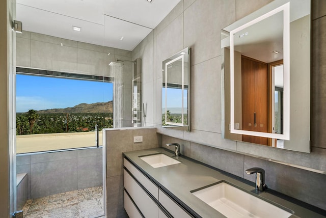 bathroom with tile walls, vanity, and a shower with door