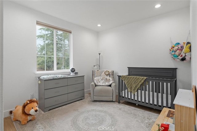 bedroom featuring light hardwood / wood-style flooring and a crib