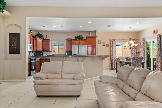 tiled living room with a healthy amount of sunlight and a chandelier