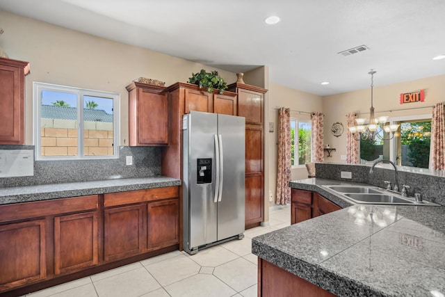 kitchen featuring sink, light tile patterned floors, tasteful backsplash, stainless steel fridge with ice dispenser, and hanging light fixtures