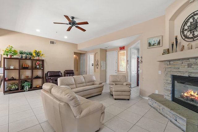 tiled living room with ceiling fan and a fireplace