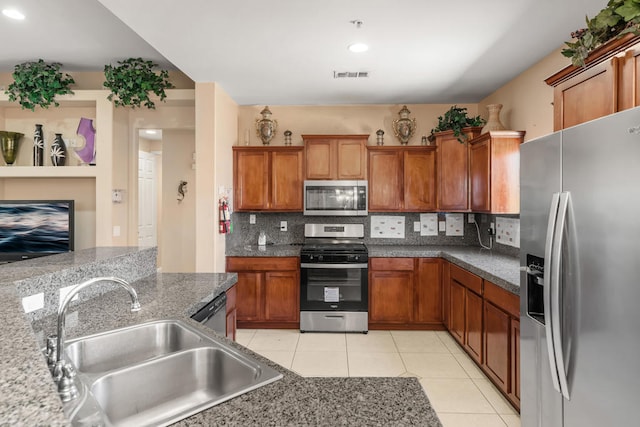 kitchen featuring decorative backsplash, appliances with stainless steel finishes, light tile patterned floors, sink, and dark stone countertops