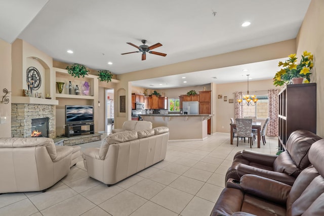 living room featuring ceiling fan with notable chandelier, a fireplace, light tile patterned flooring, and a healthy amount of sunlight