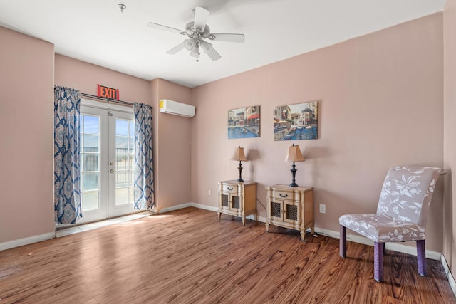 sitting room featuring ceiling fan, an AC wall unit, french doors, and wood-type flooring