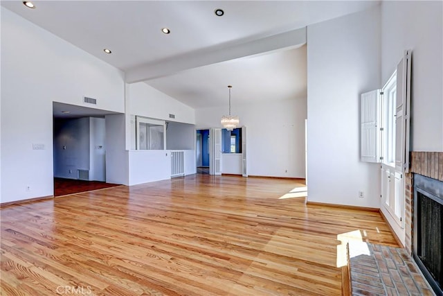 unfurnished living room with light hardwood / wood-style flooring, a fireplace, vaulted ceiling with beams, and a notable chandelier