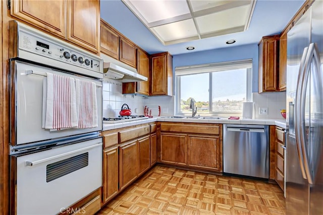 kitchen with decorative backsplash, appliances with stainless steel finishes, sink, and tile countertops