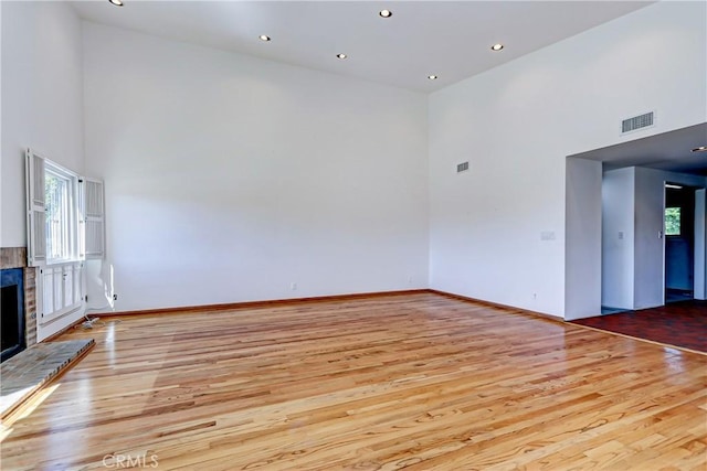 empty room with a high ceiling and light hardwood / wood-style flooring