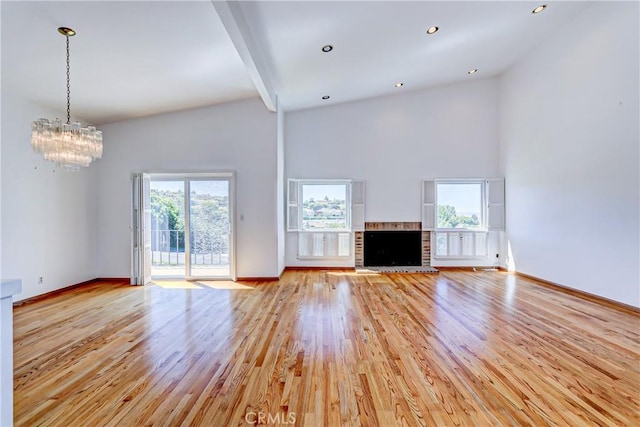 unfurnished living room featuring a high ceiling, light hardwood / wood-style flooring, beam ceiling, and a notable chandelier