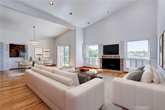 living room featuring high vaulted ceiling, light wood-type flooring, a fireplace, and beamed ceiling