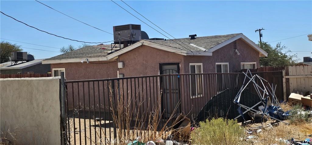 view of side of home with fence, central AC unit, and stucco siding