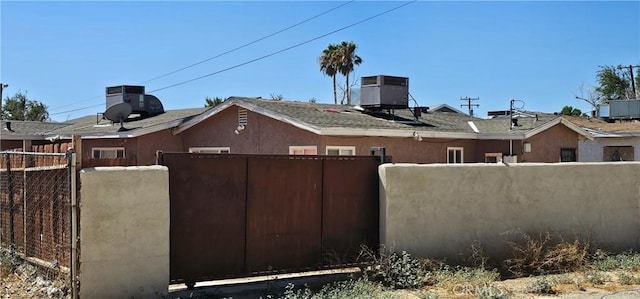 view of side of property with central air condition unit, fence, and stucco siding