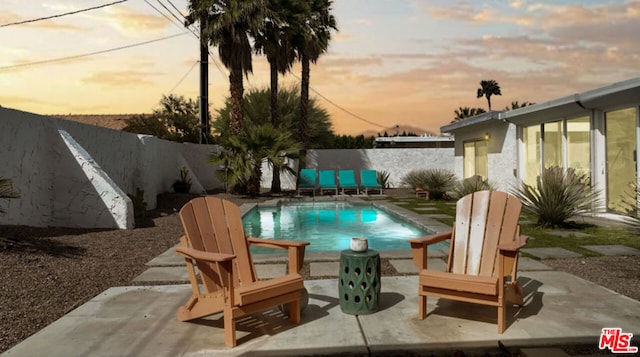 pool at dusk with a patio area