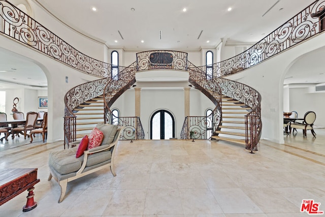 foyer with french doors, a towering ceiling, and decorative columns