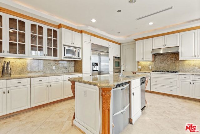 kitchen featuring built in appliances, white cabinetry, and an island with sink