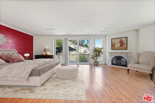 bedroom with ornamental molding, access to outside, a fireplace, and hardwood / wood-style floors