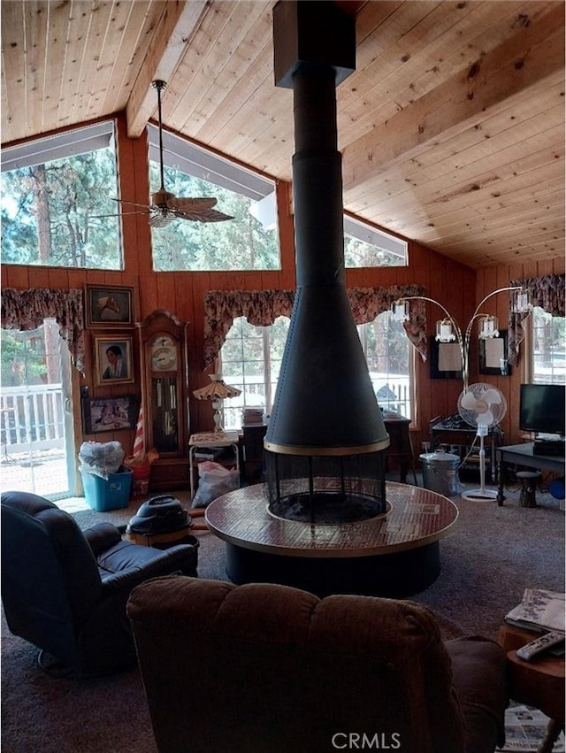 living room featuring wooden walls, carpet, beam ceiling, and a wood stove