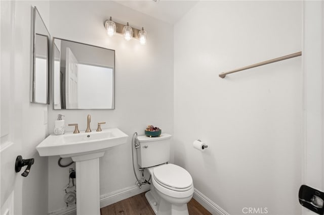 bathroom with a sink, wood finished floors, toilet, and baseboards