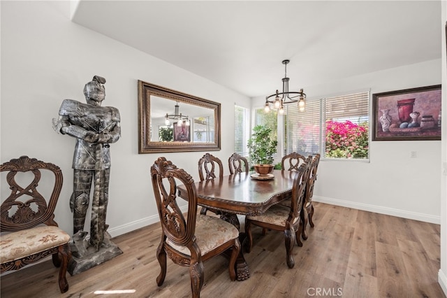 dining area featuring a chandelier, light wood-type flooring, and baseboards