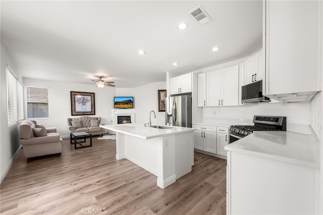 kitchen featuring visible vents, white cabinets, appliances with stainless steel finishes, open floor plan, and a kitchen island with sink