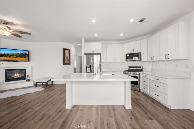 kitchen with white cabinetry, appliances with stainless steel finishes, a center island with sink, and sink